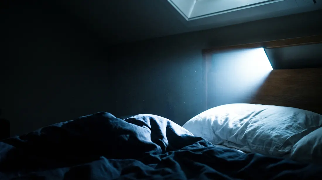 A phone’s cold glare washing across the pillow beside you in a dark bedroom